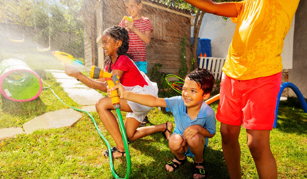 Group of kids play water gun fight game outside to limit screen time