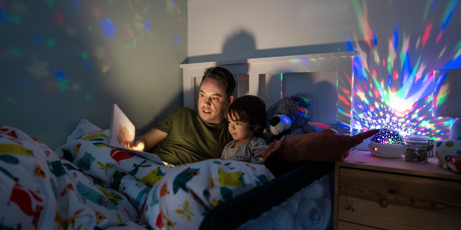 His father is reading him a bedtime story out of a book