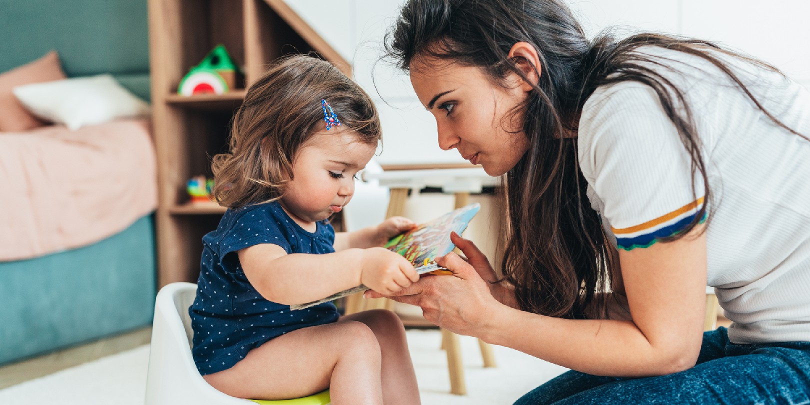 Young Mother training her toddler girl to use the potty