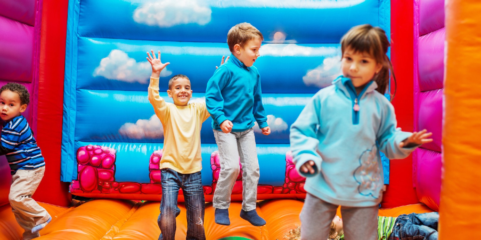 third-birthday-party-ideas mighty-moms Cheerful group of children enjoying while playing in the bouncy castle.
