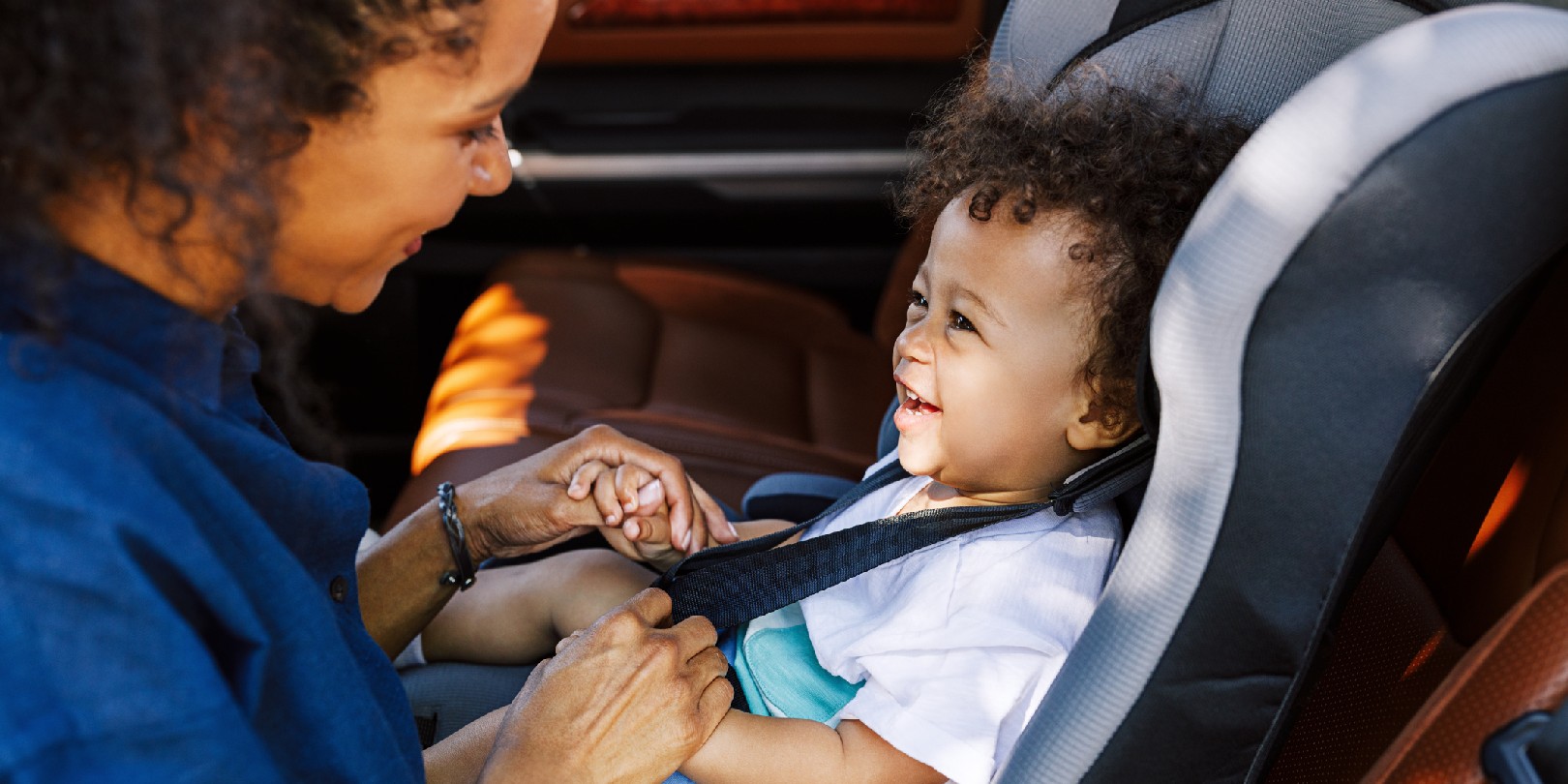 Side view of a mother helping toddler get buckled into his car seat