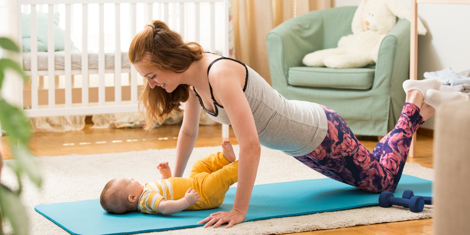 Young mother working out at home on a mat with baby.