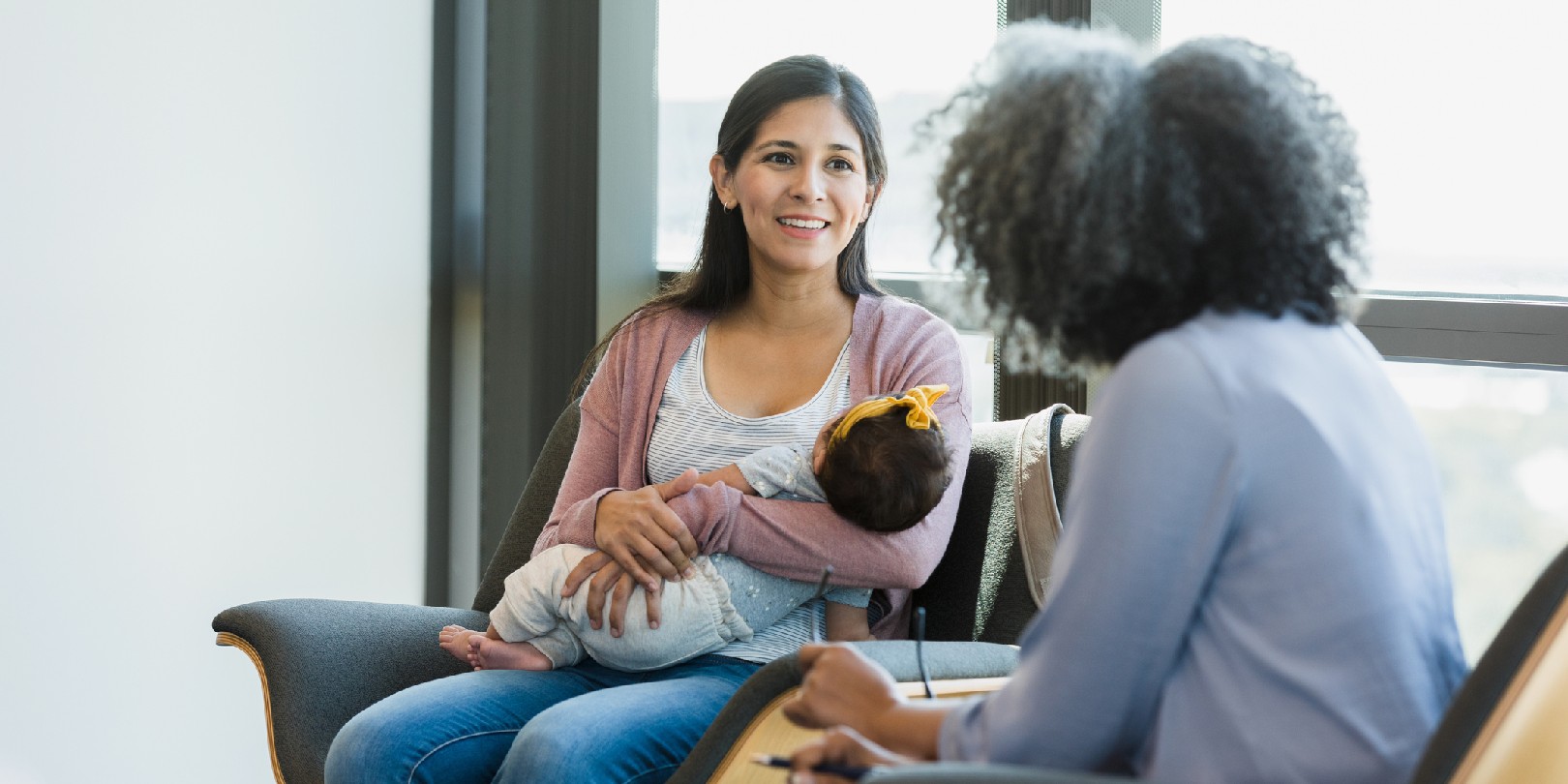 As the unrecognizable mature adult female therapist shares advice, the mid adult new mother smiles.