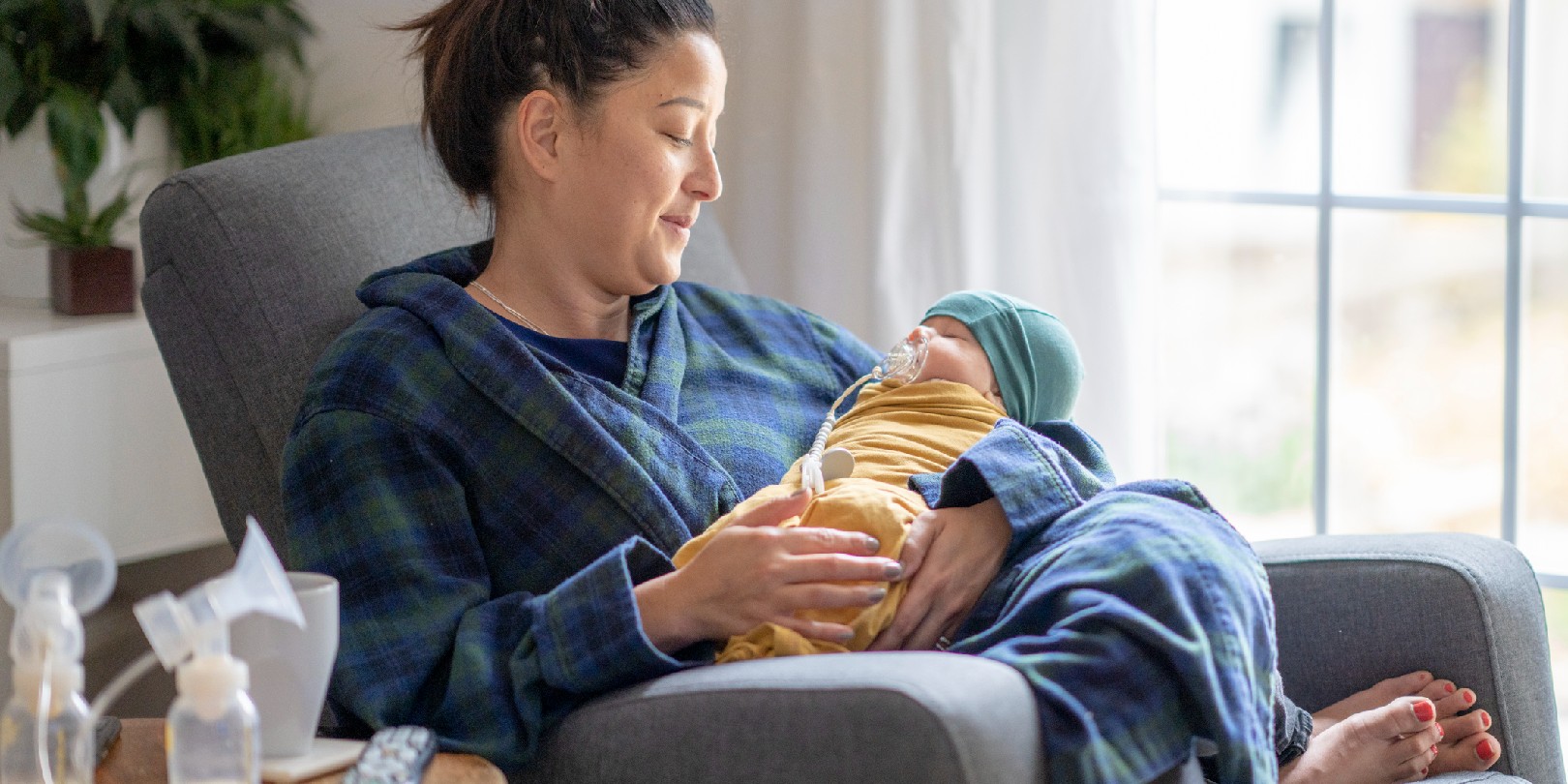 Tired mother holding her newborn child at home after tying to pump.