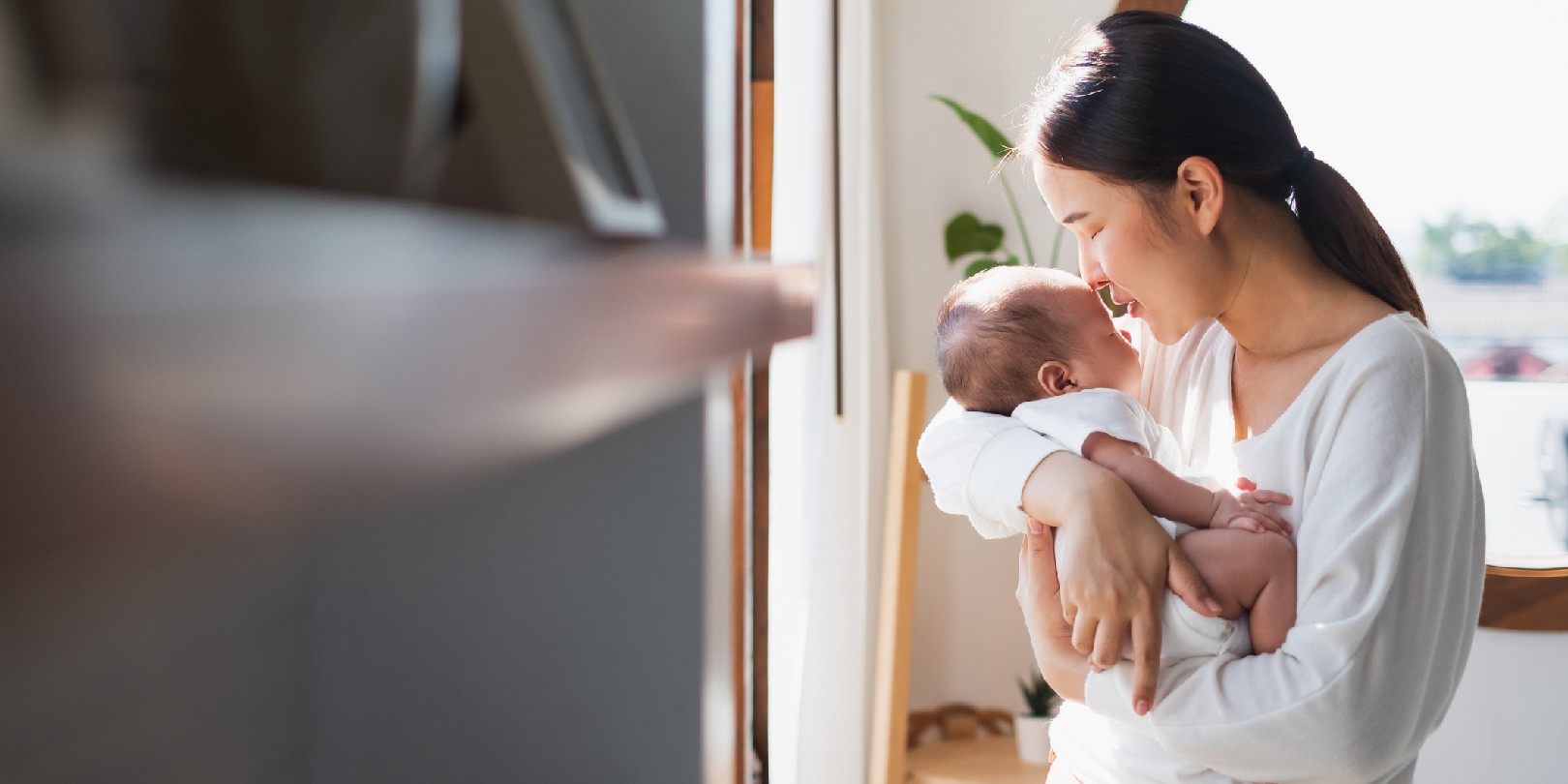 Young Asian mother holding her newborn baby in bedroom