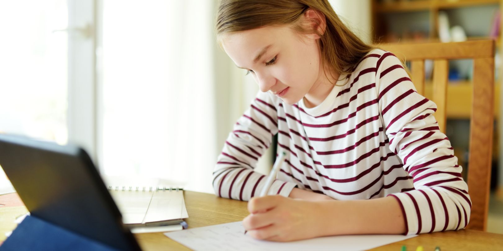 Smart Preteen Schoolgirl Doing Her Homework with Digital Tablet at Home. Education and Distance Learning for Kids. Homeschooling during Quarantine.