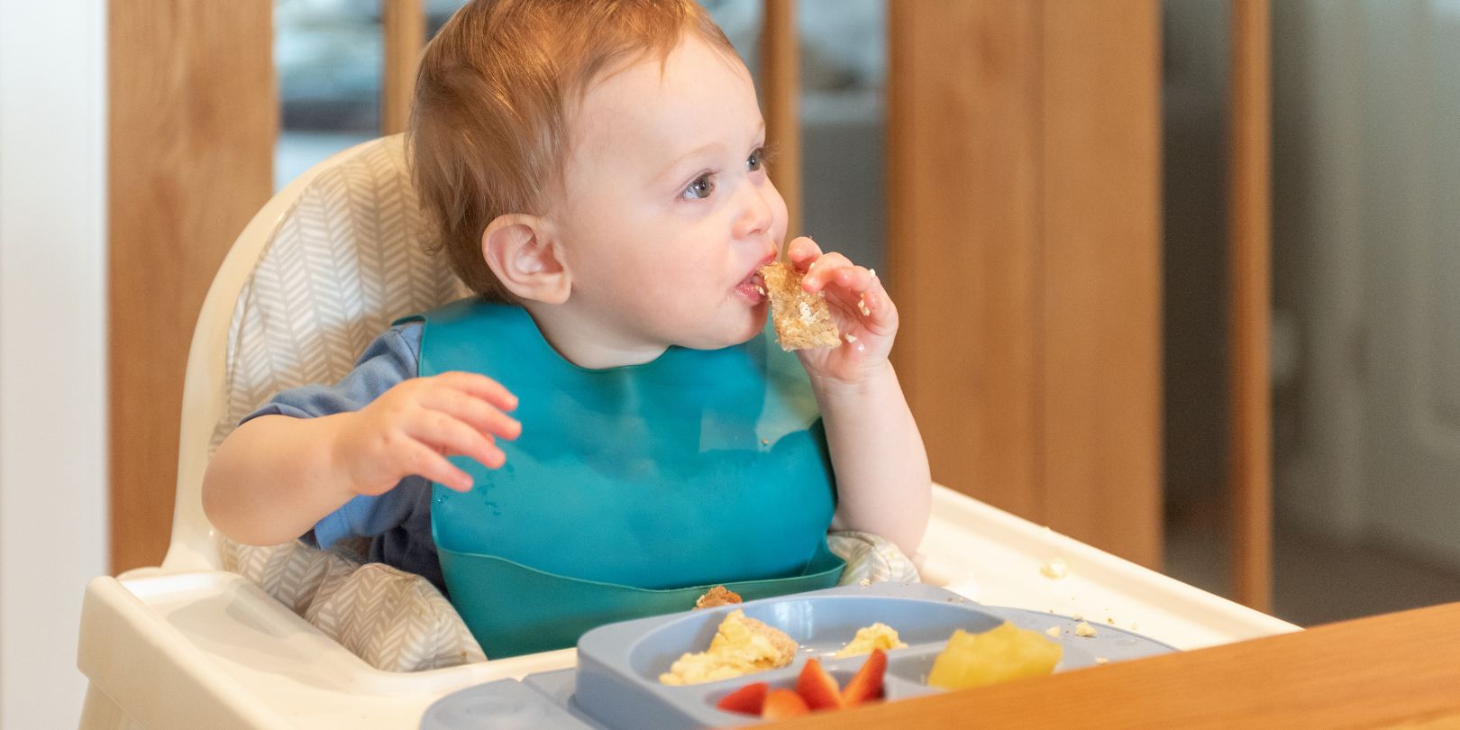 Baby led weaning, 10 month old baby feeding himself sat in high chair