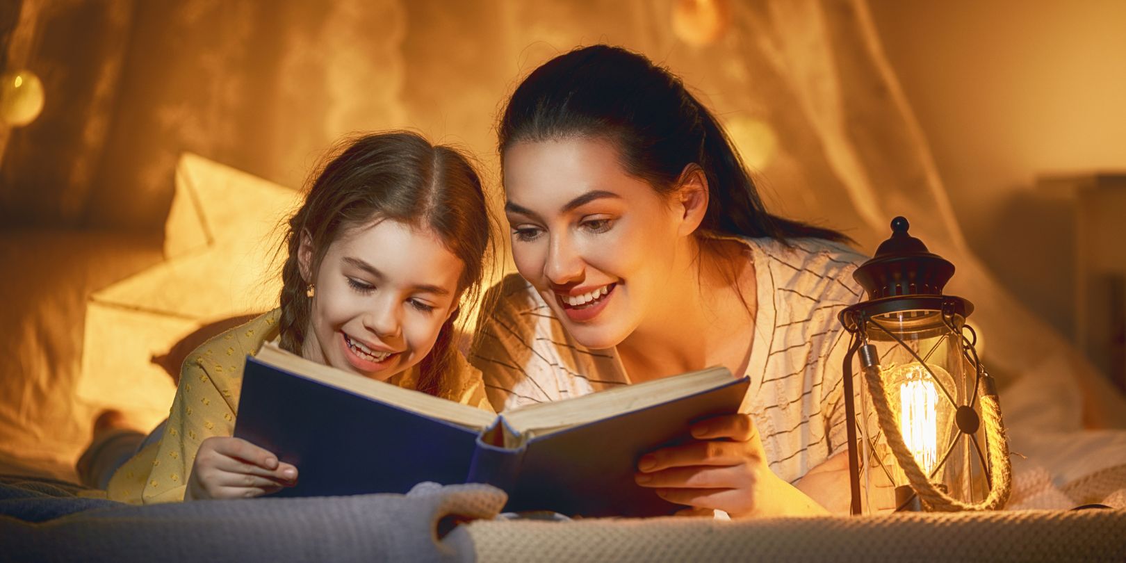 Family time. Pretty young mother reading a book to her daughter. Happy time at home.