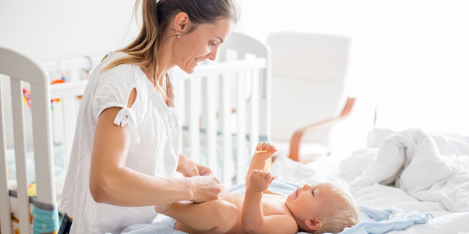 Young mom, changing baby diaper after bath