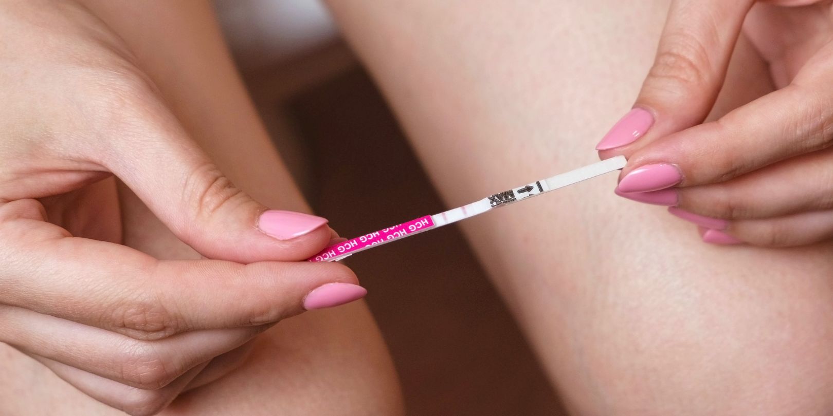 Woman makes a pregnancy test. Waiting for the result, looking at the test strip. Two stripes on test. Close-up hands and legs.