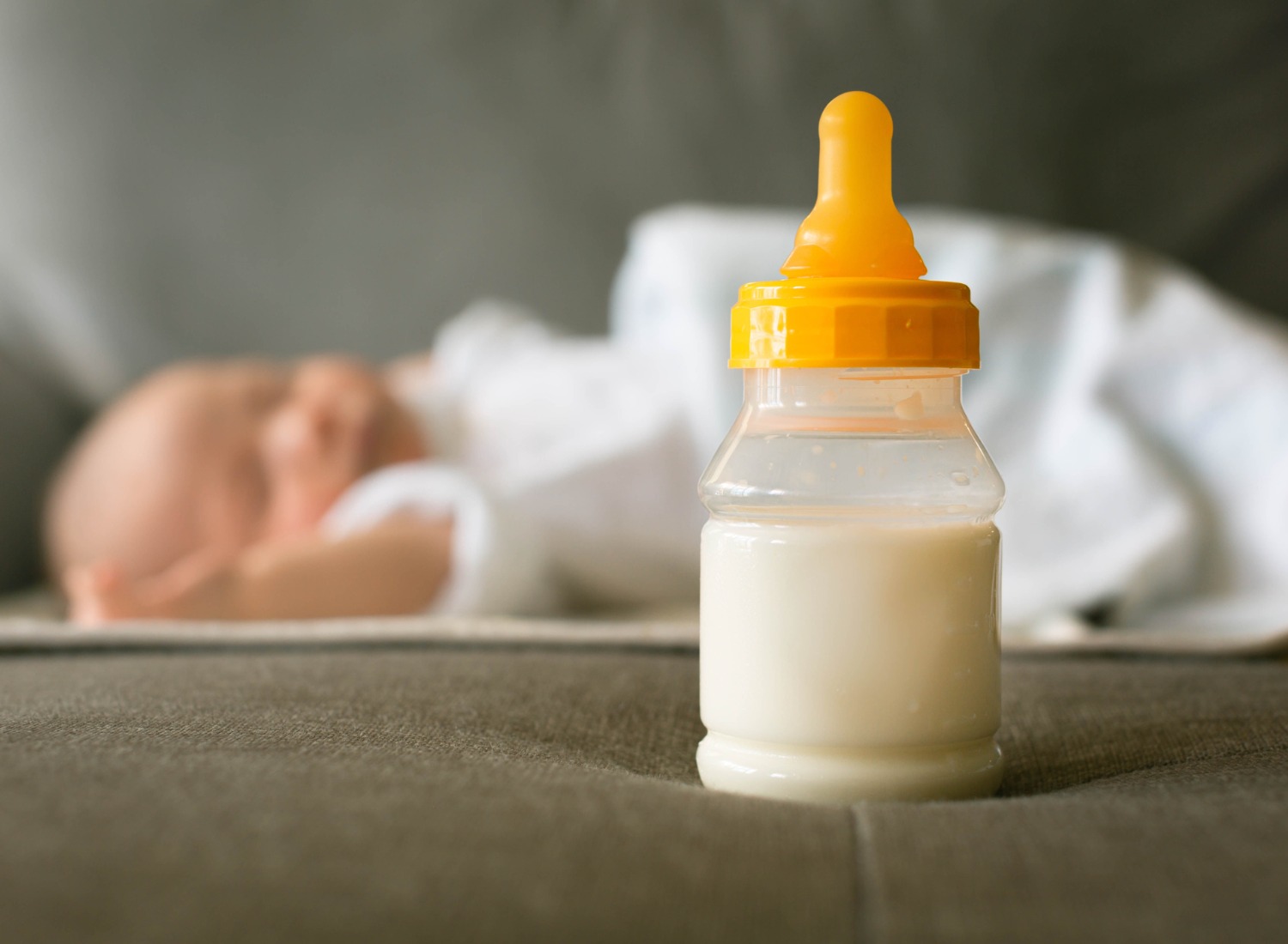 A bottle of milk near a sleeping baby