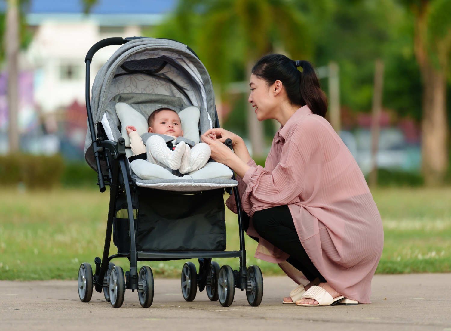 A woman playing with her baby in a stroller