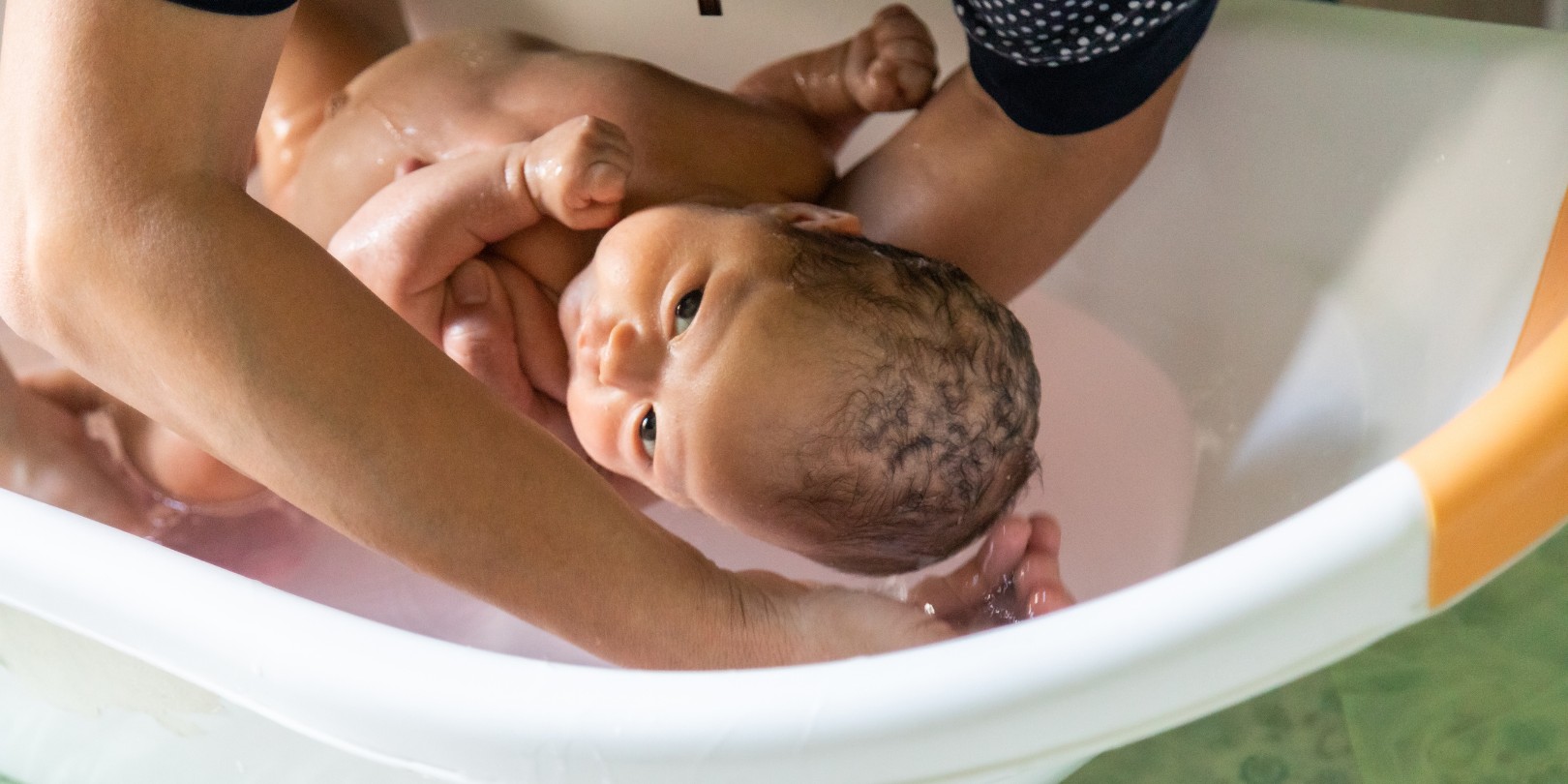 Closeup of newborn baby bathing in a baby bath