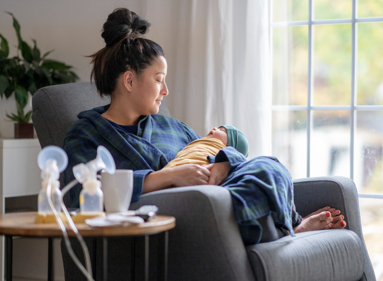 Mother holding baby next to breast pump accessories