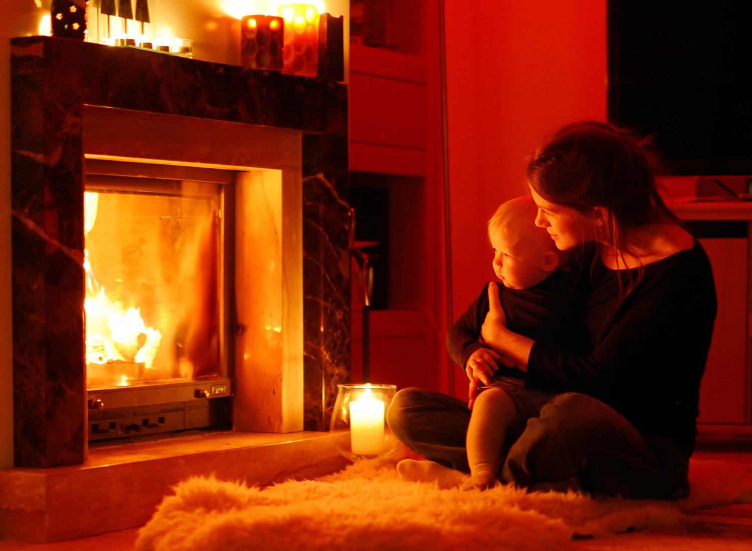 Woman holding a baby next to a fireplace