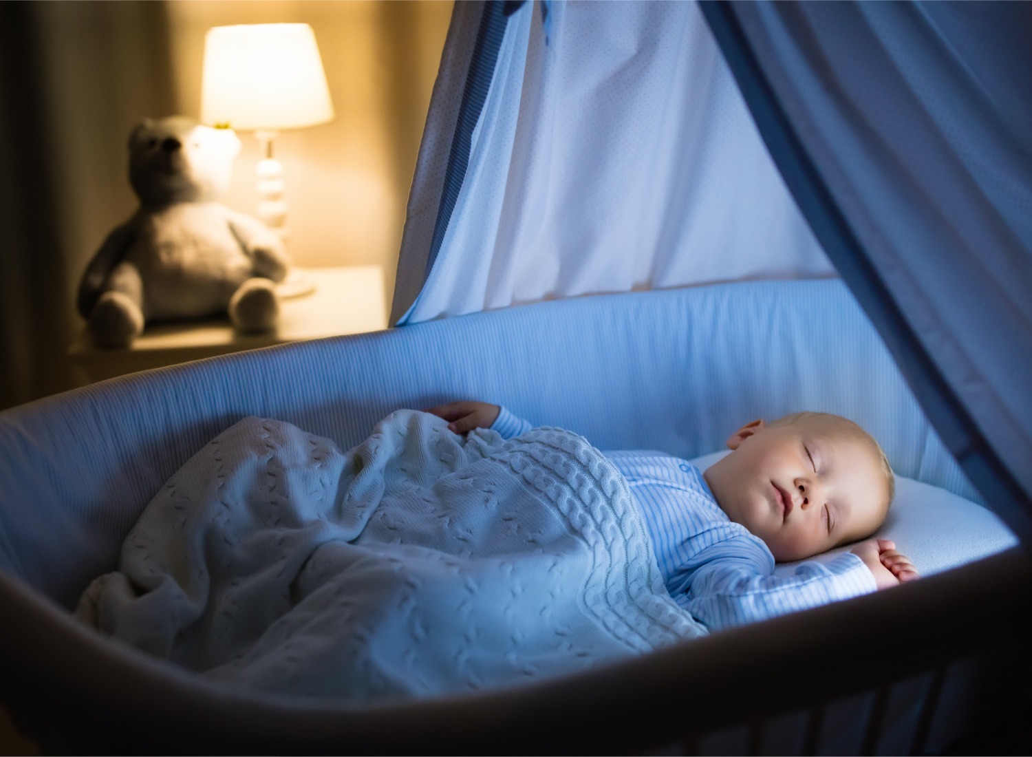 Baby sleeping in blue bassinet