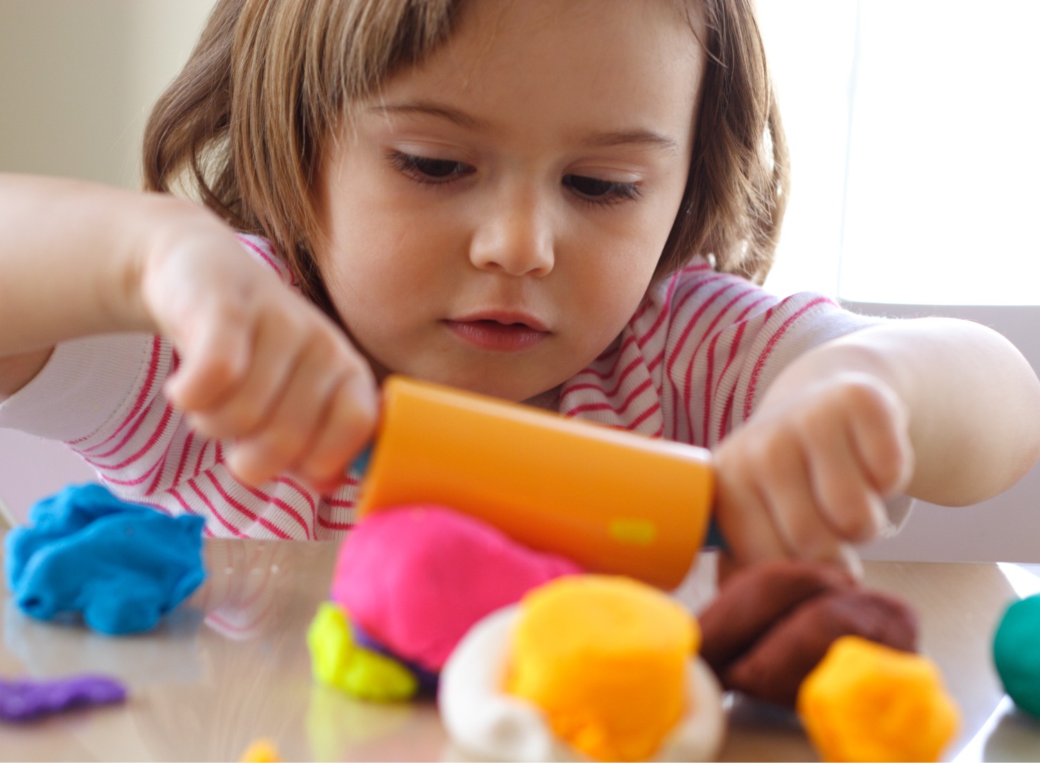 Child playing with play doh rolling pin