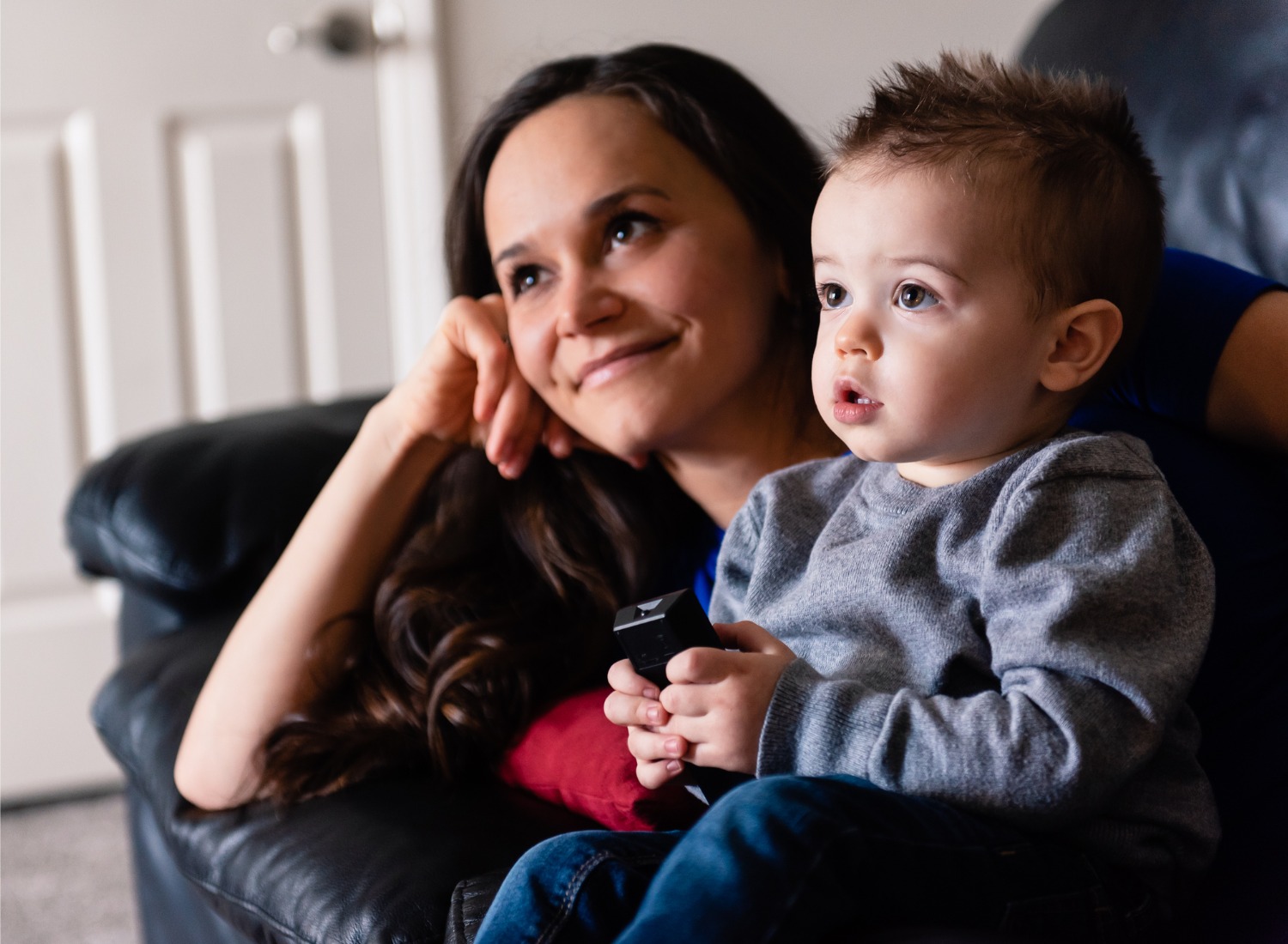 Toddler watching tv with his mom