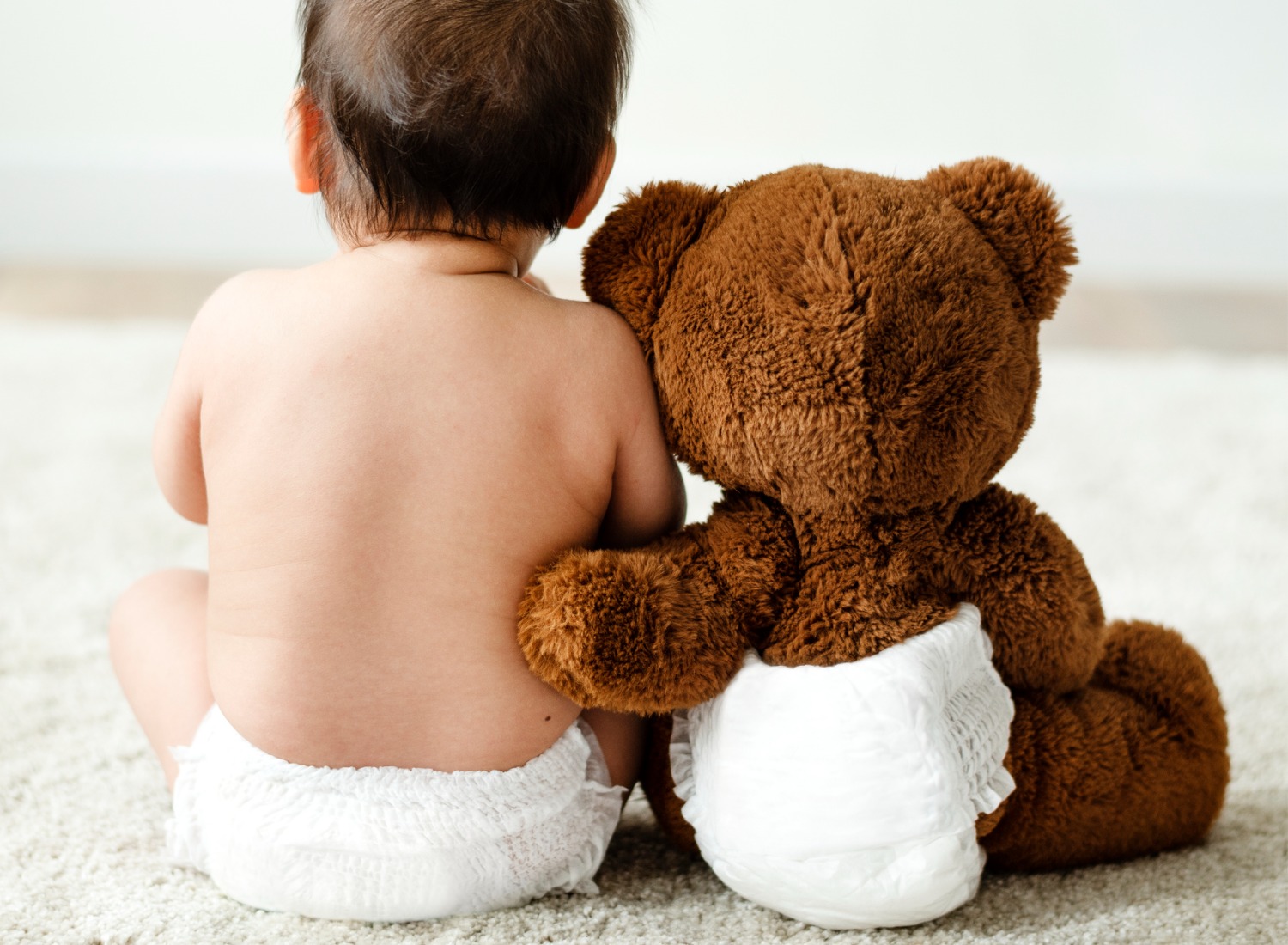 Baby and teddy bear wearing diapers