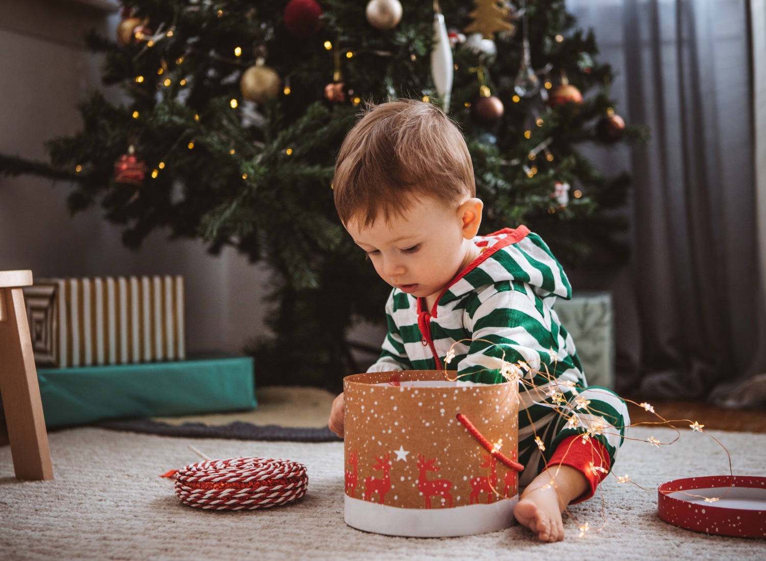 Toddler opening a box near Christmas tree