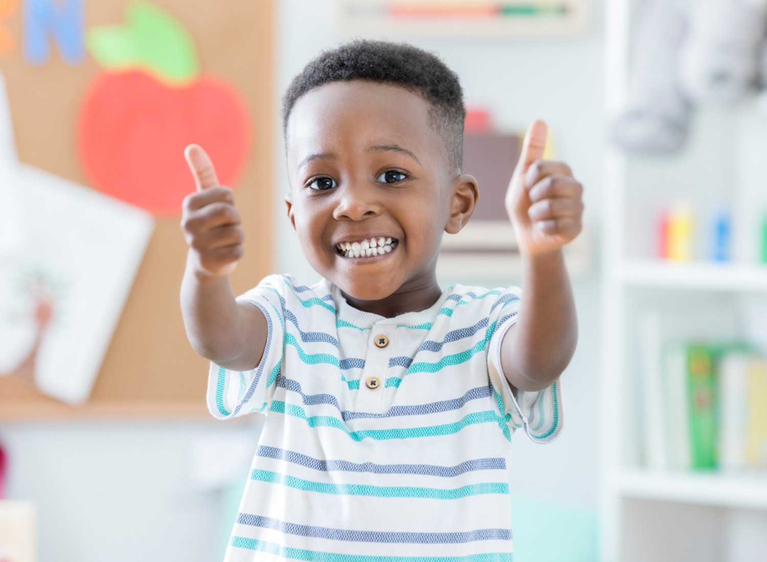 Child smiling and giving a thumbs-up